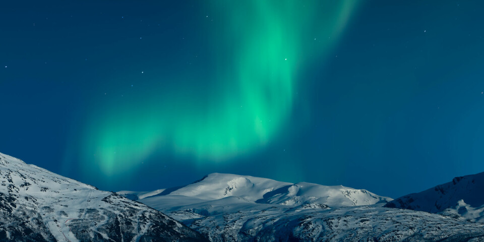 Northern,Lights,Above,Snow,Covered,Mountains,And,The,Town,Of