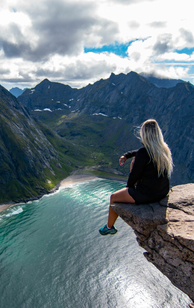 Adventurous,Woman,Looking,Down,At,Kvalvika,Beach,In,Lofoten,,Norway
