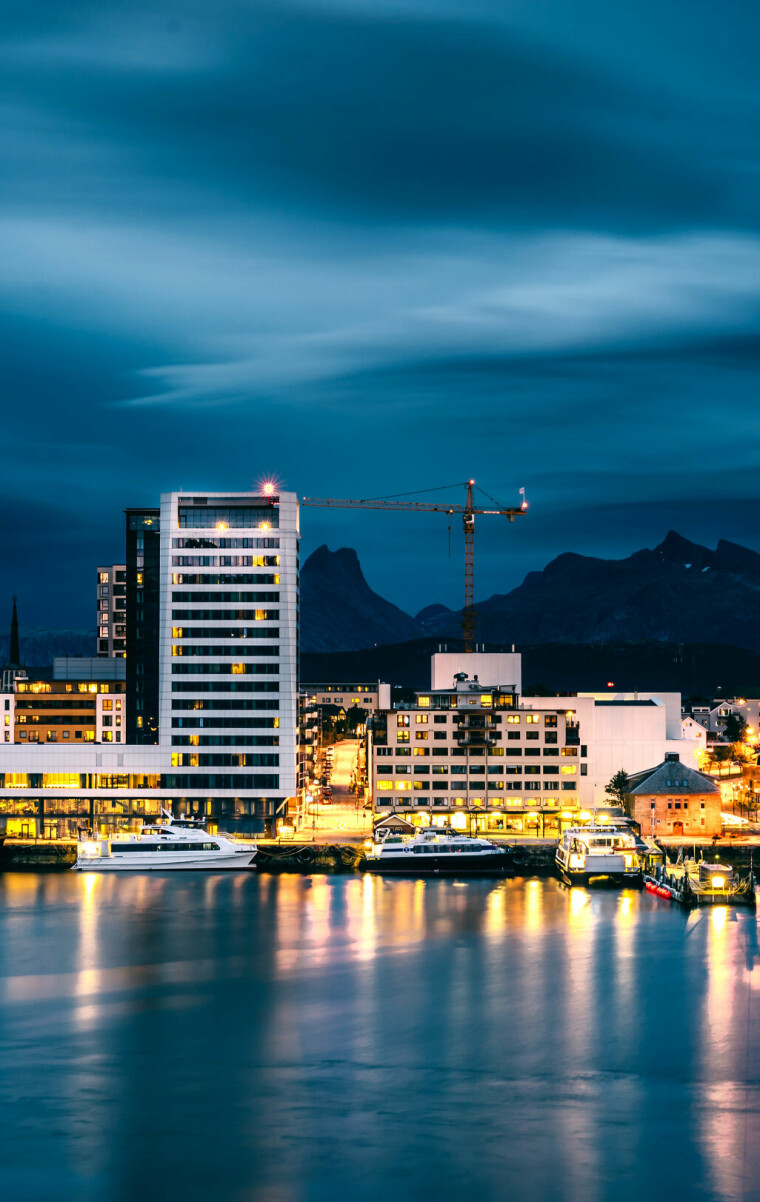 A long exposure photograph of Bodø city at night with dramatic clouds