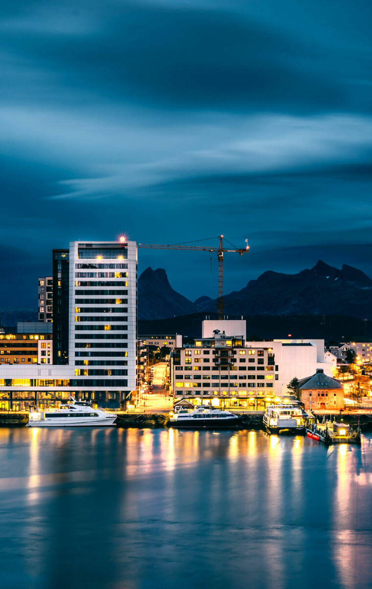 A long exposure photograph of Bodø city at night with dramatic clouds