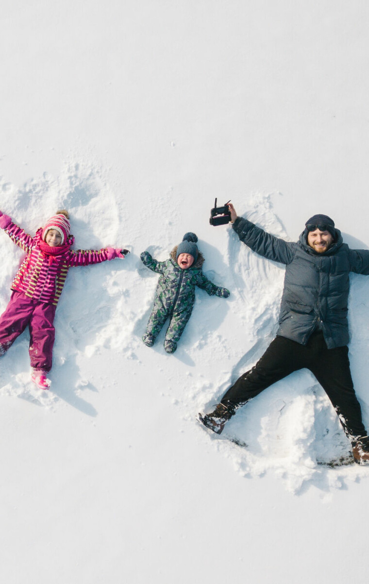 Family,Making,A,Snow,Angel.,Aerial,View.,Mother,And,Father
